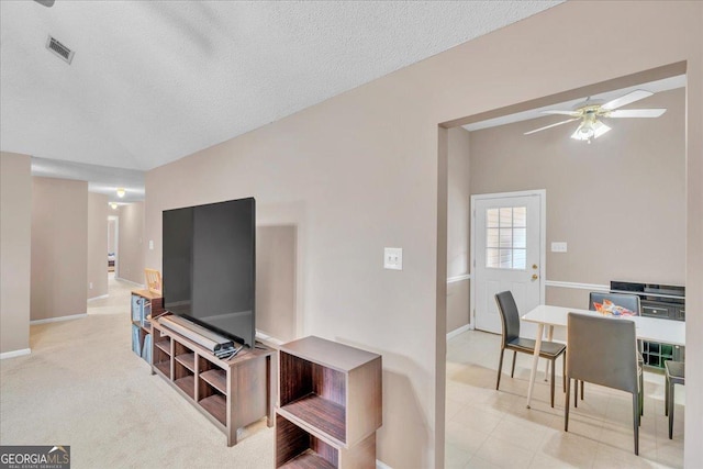 living room with baseboards, visible vents, a ceiling fan, light colored carpet, and a textured ceiling