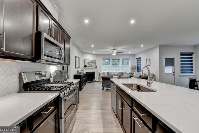 kitchen with backsplash, appliances with stainless steel finishes, light wood-type flooring, a sink, and recessed lighting