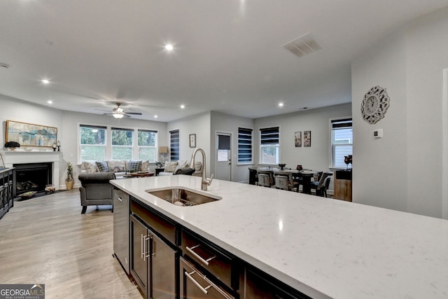 kitchen featuring visible vents, a fireplace, a sink, stainless steel dishwasher, and open floor plan