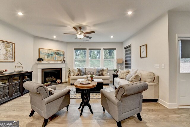 living room with recessed lighting, light wood-type flooring, baseboards, and a glass covered fireplace