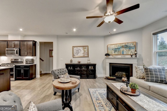 living room featuring light wood-style floors, a fireplace, a ceiling fan, and recessed lighting