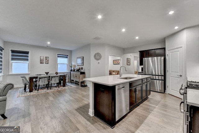 kitchen with a sink, light wood-style floors, appliances with stainless steel finishes, and light countertops