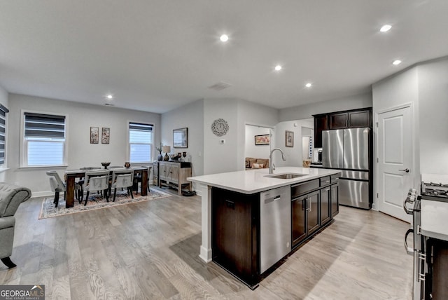 kitchen featuring light countertops, a sink, light wood finished floors, and stainless steel appliances