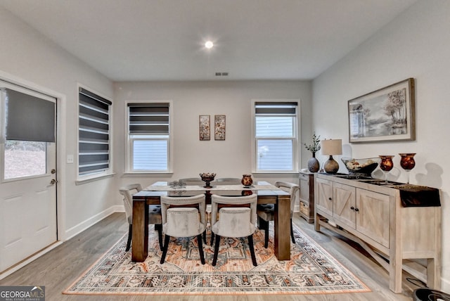 dining area featuring light wood-style floors, visible vents, and baseboards