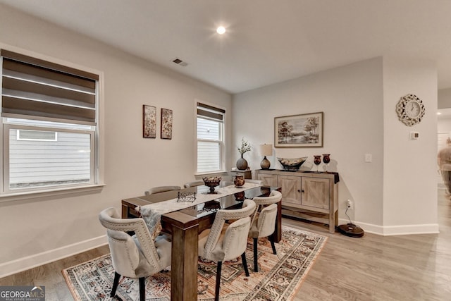 dining room with light wood finished floors, visible vents, and baseboards