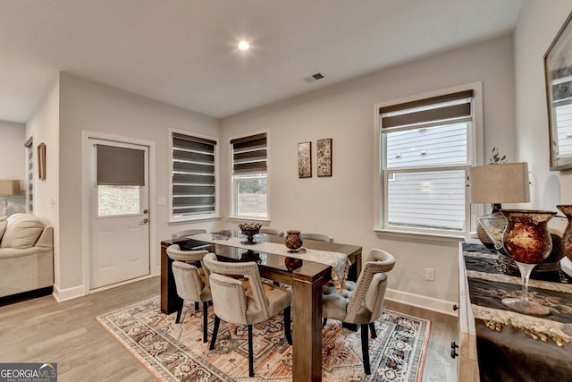 dining space featuring baseboards, visible vents, and light wood finished floors