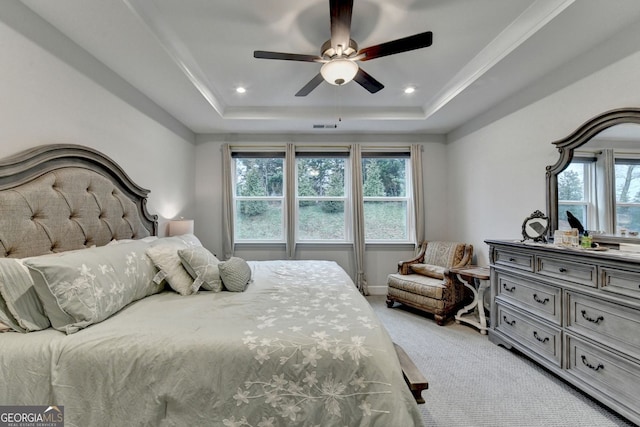 bedroom with light colored carpet, a tray ceiling, multiple windows, and visible vents