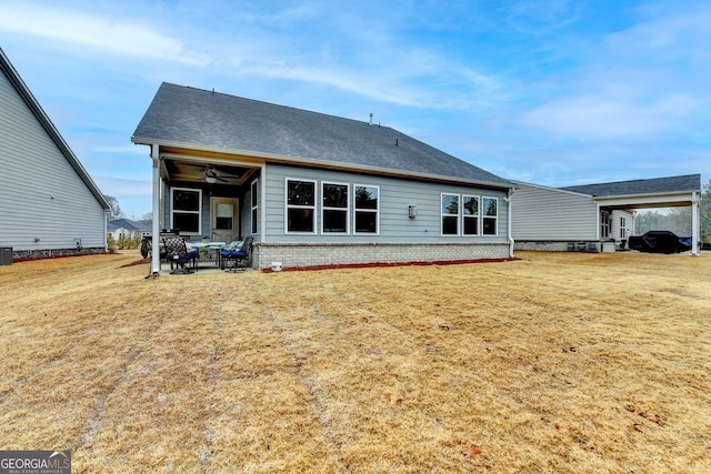 rear view of house with a lawn, a ceiling fan, central AC, brick siding, and a patio area