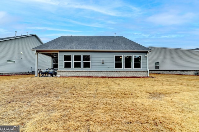 rear view of property with brick siding, roof with shingles, and a lawn