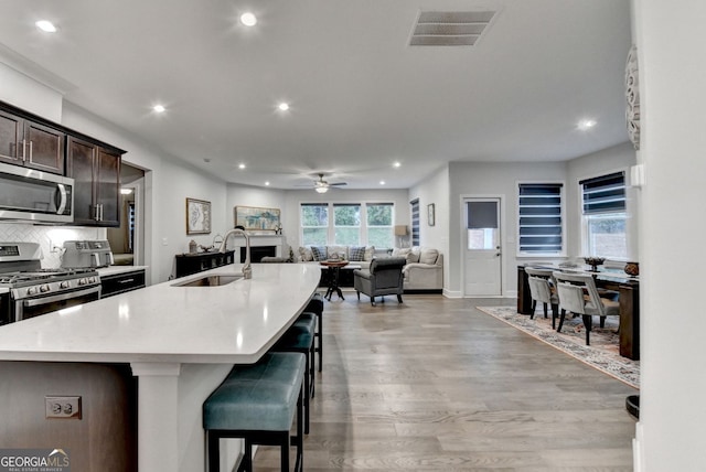 kitchen with dark brown cabinetry, a ceiling fan, visible vents, appliances with stainless steel finishes, and a sink