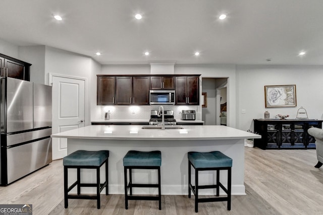 kitchen with light countertops, a sink, a breakfast bar area, and stainless steel appliances