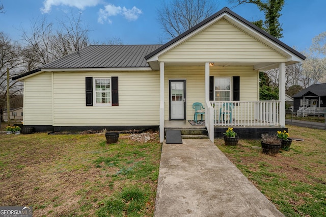 view of front of house with metal roof, a porch, and a front lawn