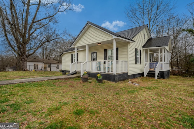 view of front of property featuring covered porch, metal roof, and a front lawn