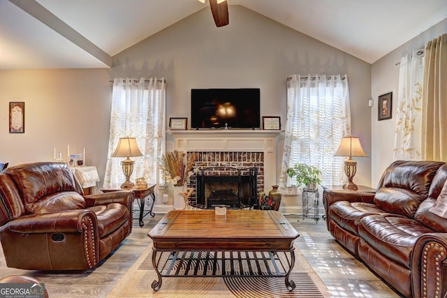 living room featuring vaulted ceiling, a fireplace, wood finished floors, and a healthy amount of sunlight