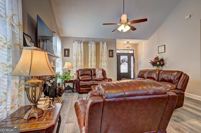 living area with ceiling fan, vaulted ceiling, baseboards, and wood finished floors