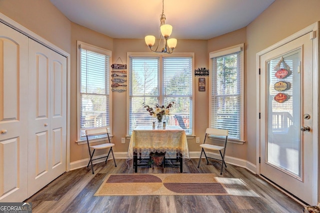 dining space featuring a chandelier, baseboards, and wood finished floors