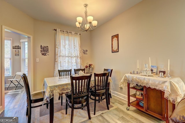 dining space featuring a notable chandelier, baseboards, and wood finished floors