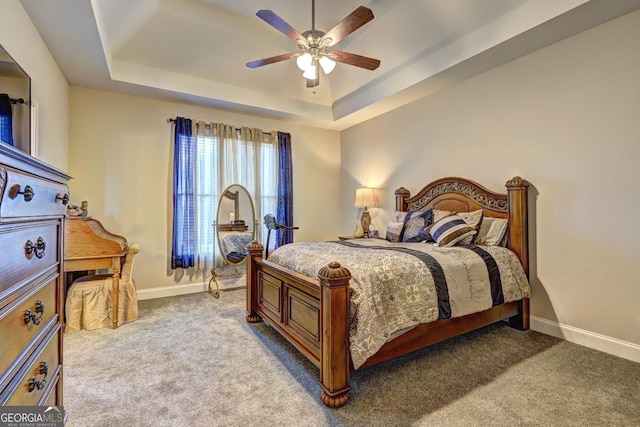 bedroom featuring carpet floors, a raised ceiling, a ceiling fan, and baseboards