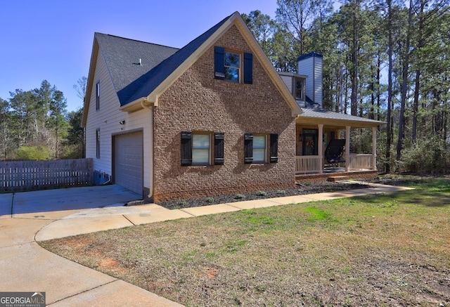 view of front of home with covered porch, a garage, concrete driveway, a chimney, and a front yard