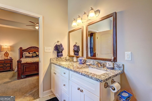 bathroom with ensuite bathroom, double vanity, a sink, and a ceiling fan