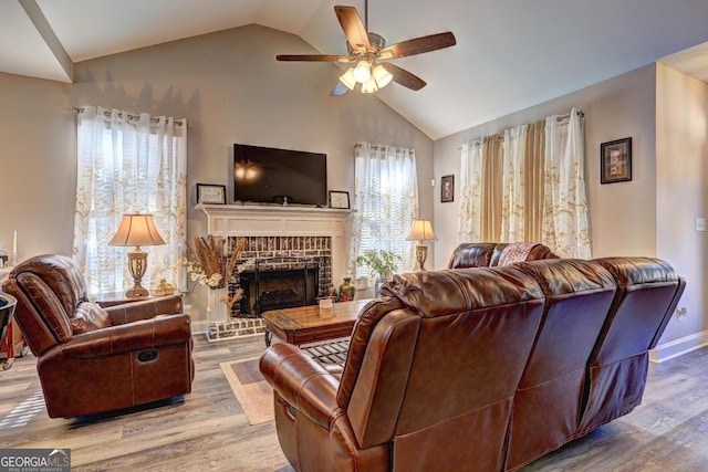 living room featuring lofted ceiling, a brick fireplace, a ceiling fan, and wood finished floors