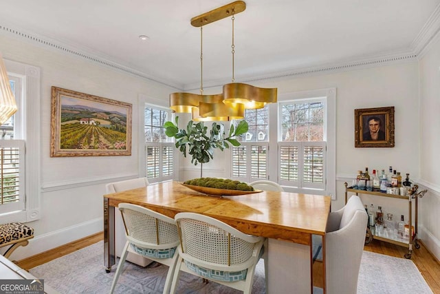 dining space featuring a wainscoted wall, wood finished floors, and crown molding