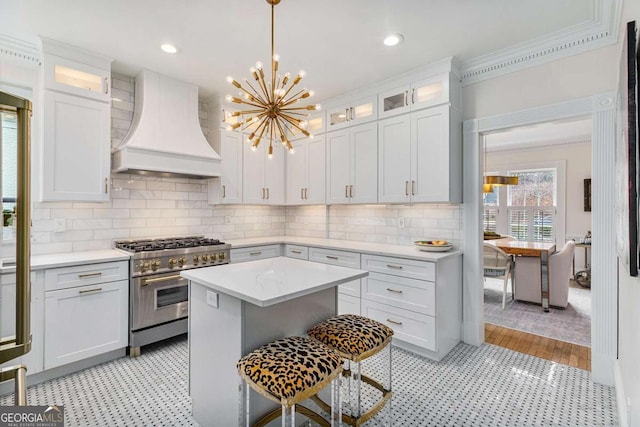 kitchen with custom exhaust hood, white cabinets, stainless steel stove, and light countertops