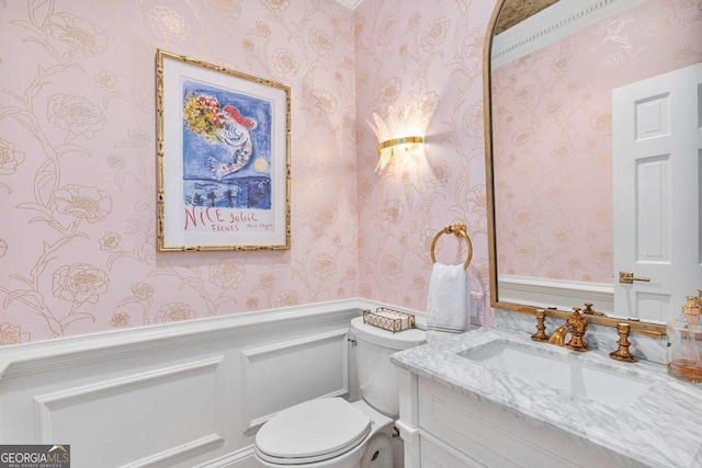 half bath featuring wallpapered walls, toilet, and vanity