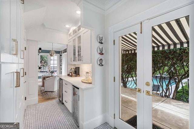 doorway featuring a dry bar, beverage cooler, crown molding, and vaulted ceiling