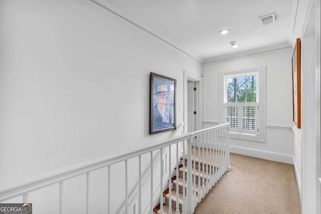 corridor with visible vents, crown molding, a wainscoted wall, light carpet, and an upstairs landing