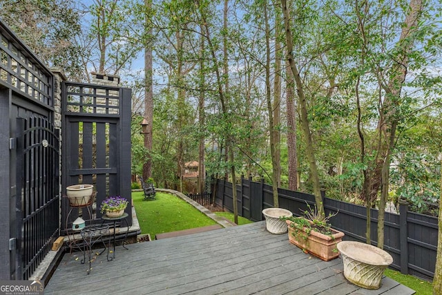 wooden terrace featuring a yard and fence