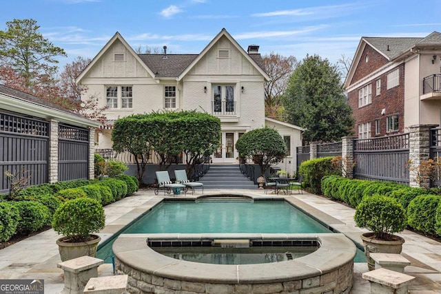 back of property featuring fence, french doors, brick siding, an in ground hot tub, and a chimney