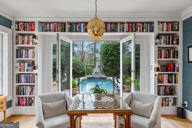 sitting room with wall of books, wood finished floors, and a wealth of natural light