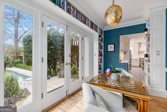 doorway featuring light wood-style flooring, ornamental molding, and wallpapered walls