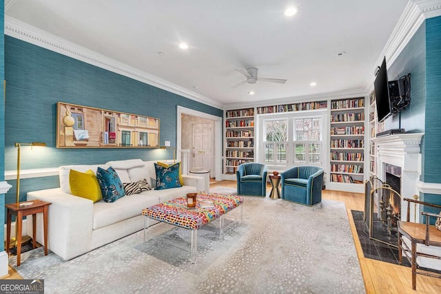 living room with a fireplace with flush hearth, ornamental molding, wood finished floors, recessed lighting, and ceiling fan