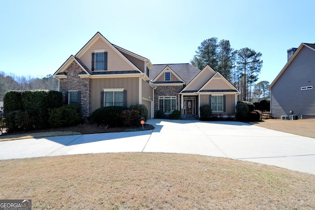 view of front of house with driveway, a standing seam roof, stone siding, board and batten siding, and a front yard