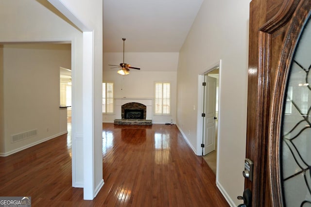 interior space with visible vents, dark wood finished floors, a fireplace, baseboards, and ceiling fan