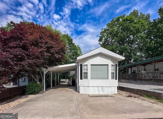 manufactured / mobile home featuring an attached carport, concrete driveway, and fence