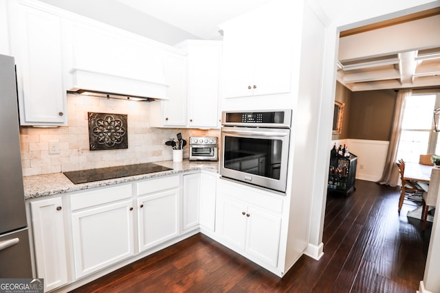 kitchen featuring tasteful backsplash, appliances with stainless steel finishes, dark wood-style flooring, light stone countertops, and white cabinetry