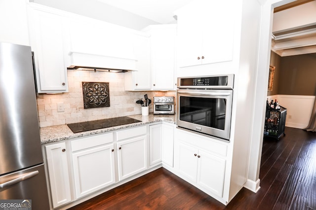 kitchen featuring stainless steel appliances, decorative backsplash, light stone counters, and dark wood-style floors