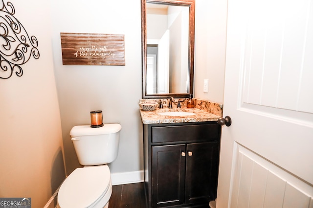 half bathroom featuring toilet, baseboards, wood finished floors, and vanity