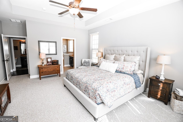 bedroom with visible vents, baseboards, ensuite bathroom, a tray ceiling, and carpet floors