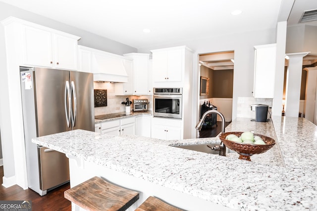 kitchen featuring stainless steel appliances, visible vents, a sink, and light stone countertops