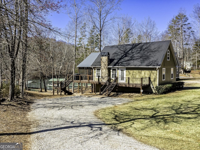 chalet / cabin featuring driveway, stairway, a deck, and a front yard