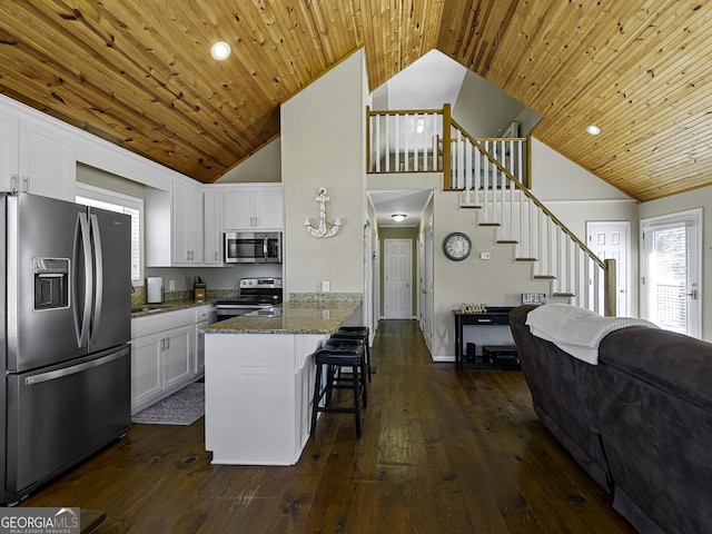 kitchen featuring appliances with stainless steel finishes, white cabinetry, dark wood finished floors, and dark stone countertops