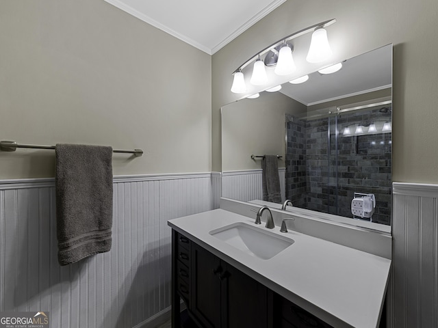 full bathroom with vanity, tiled shower, crown molding, and wainscoting