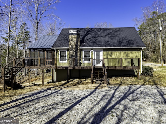 back of property featuring a chimney, metal roof, a deck, and stairs