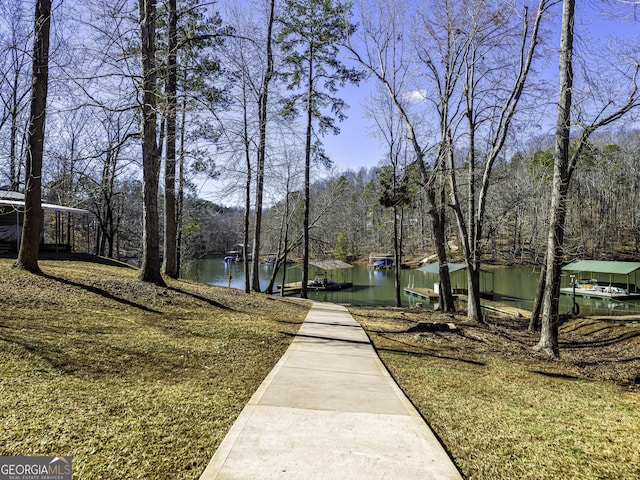 view of community with a dock, a water view, and a view of trees