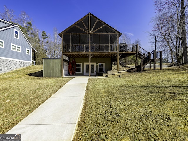 back of property with a sunroom, a yard, stairway, a wooden deck, and a patio area