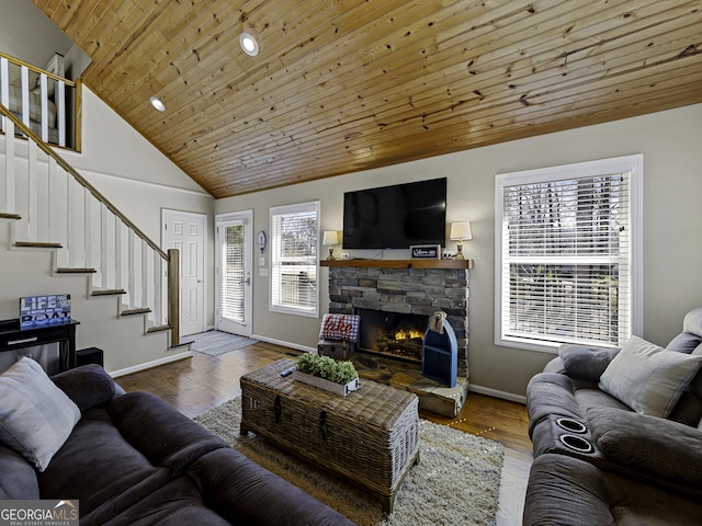 living area featuring stairway, wood ceiling, a stone fireplace, wood finished floors, and baseboards